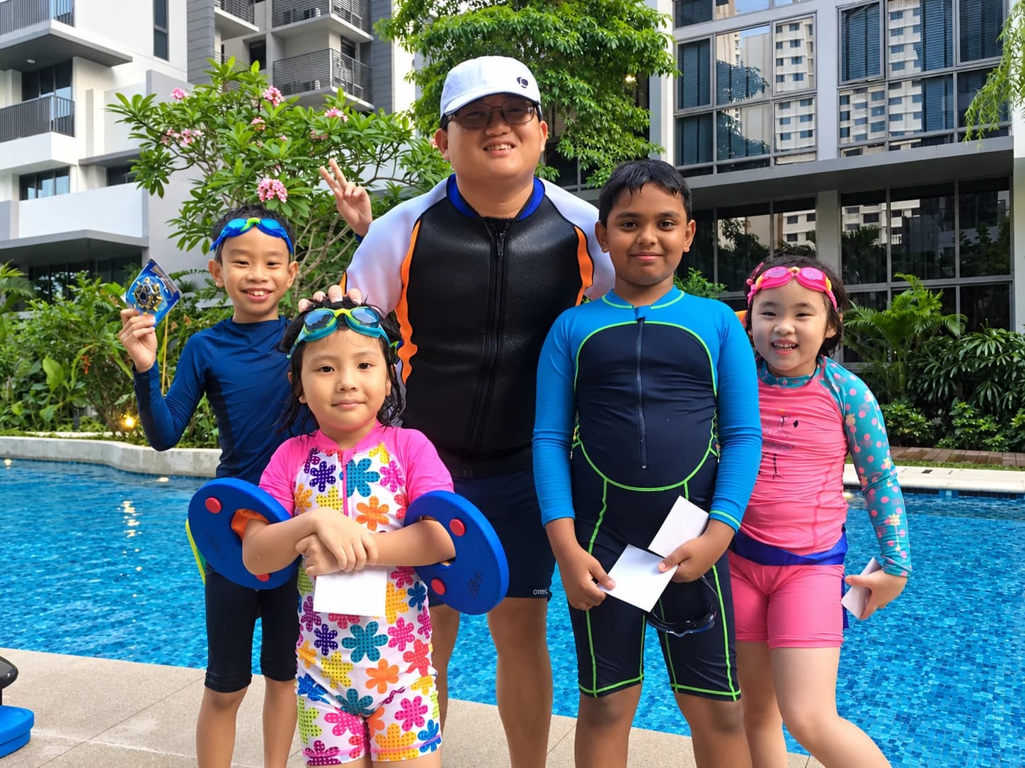 Coach with four smiling students and their float discs at a condo pool
