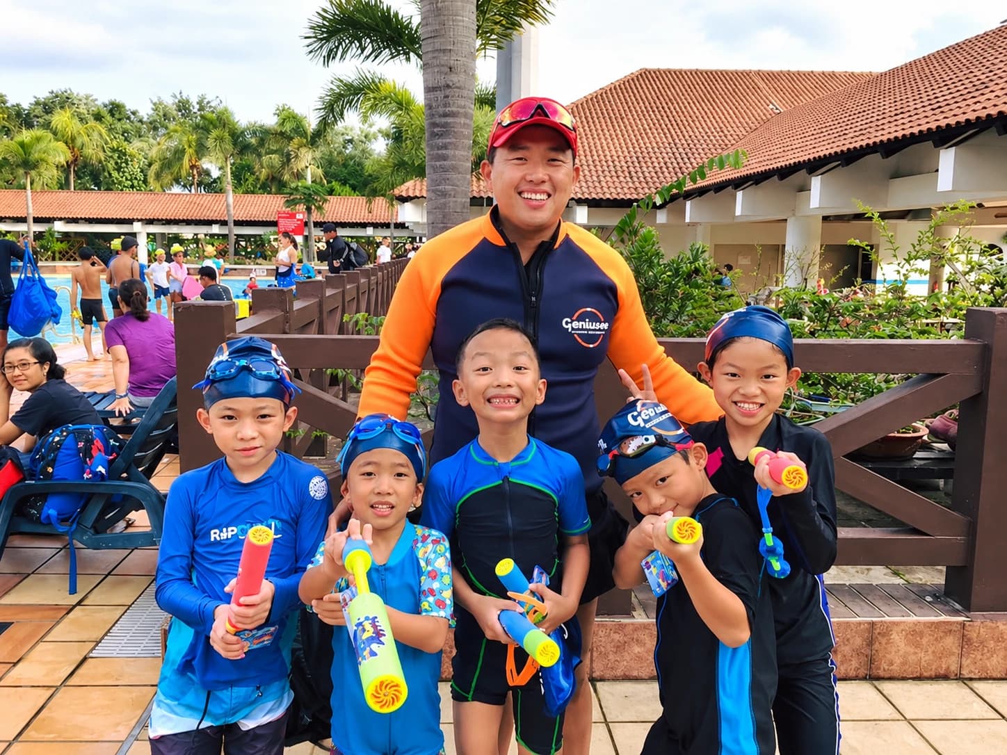 Coach with five students holding water guns at a pool club