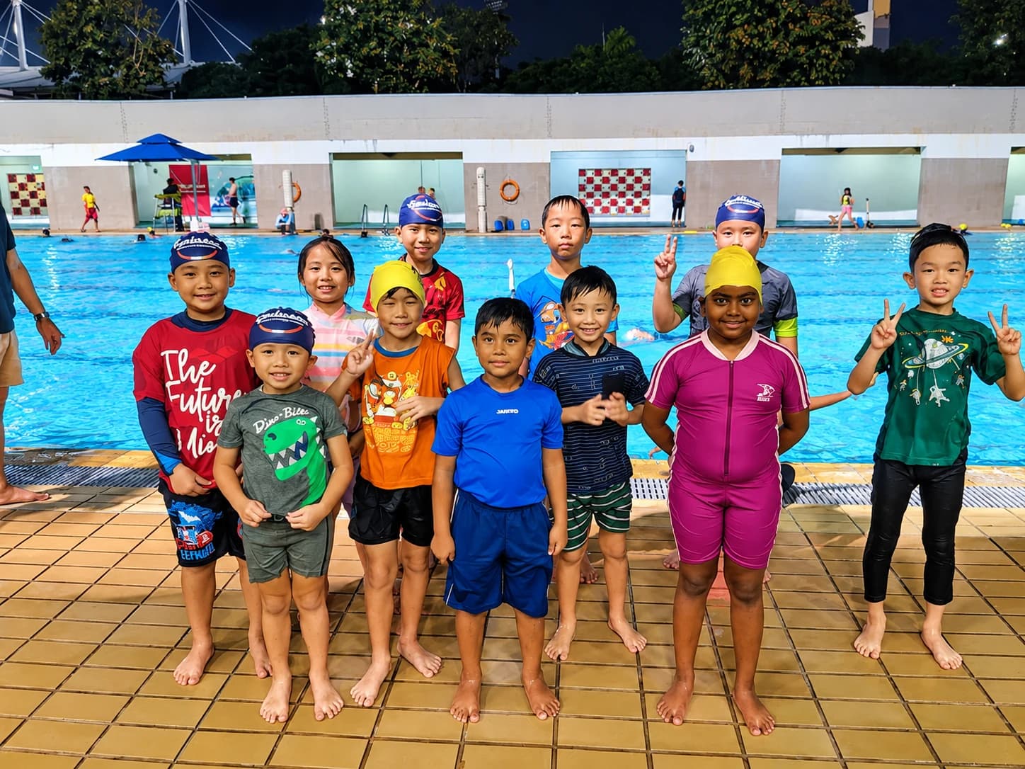 Large class of students lined up poolside for an evening lesson