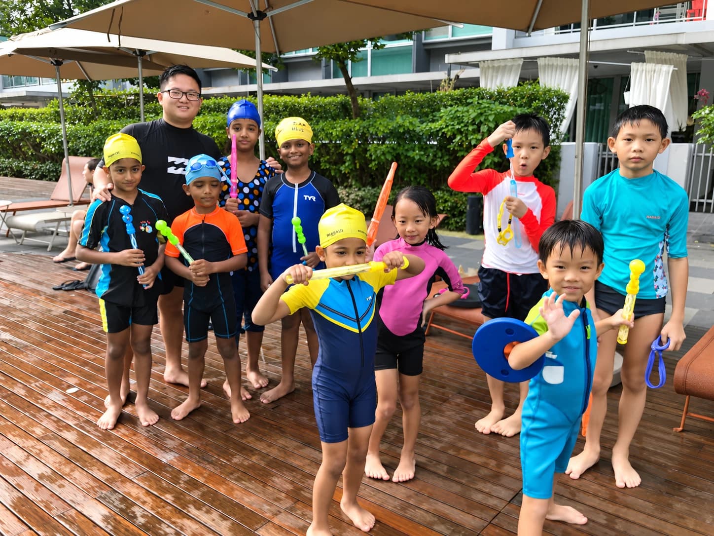 Coach with a group of kids holding bubble wands on the pool deck